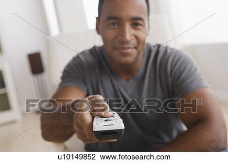 Stock Image - Mature man holding remote control, focus on foreground. Fotosearch