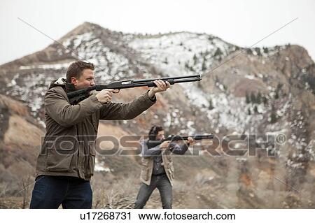 Stock Image - Men in mountains shooting. Fotosearch