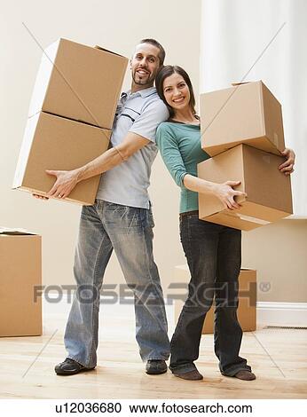 Mid adult couple carrying cardboard boxes View Large Photo Image Stock Image - Mid adult couple carrying cardboard boxes. Fotosearch