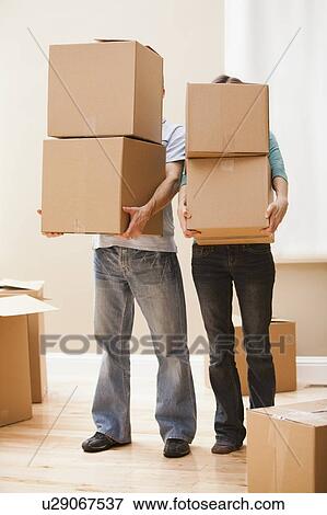 Stock Photo - Mid adult couple carrying cardboard boxes. Fotosearch
