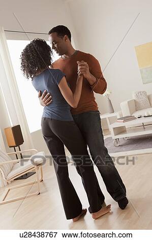 Stock Photo - Mid adult couple dancing at home. Fotosearch