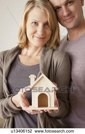Mid adult couple holding wooden model of house View Large Photo Image Stock Image - Mid adult couple holding wooden model of house. Fotosearch