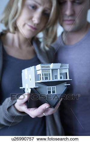 Stock Photo - Mid adult couple holding wooden model of house. Fotosearch