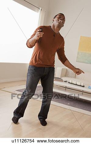 Picture - Mid adult man dancing at home. Fotosearch