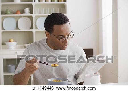 Mid adult man eating breakfast and reading newspaper View Large Photo Image Stock Image - Mid adult man eating breakfast and reading newspaper. Fotosearch
