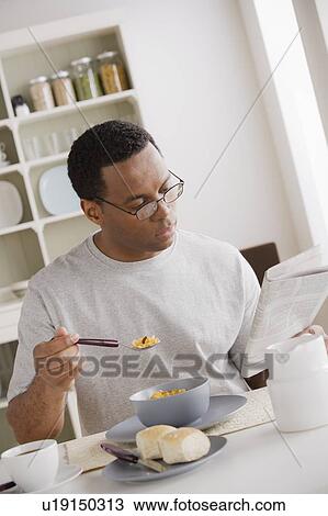 Mid adult man eating breakfast and reading newspaper View Large Photo Image Stock Image - Mid adult man eating breakfast and reading newspaper. Fotosearch