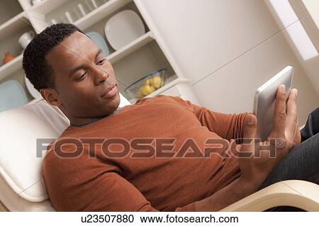 Stock Image - Mid adult man using digital tablet. Fotosearch