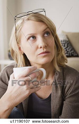 Mid adult woman drinking coffee and looking away View Large Photo Image Stock Photo - Mid adult woman drinking coffee and looking away. Fotosearch