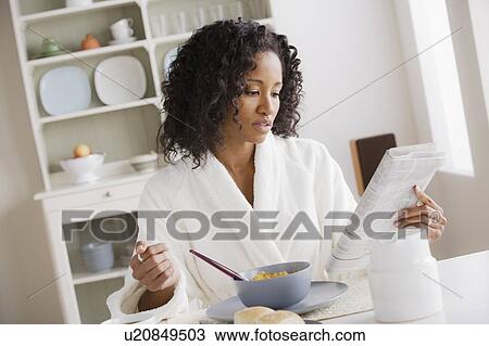 Mid adult woman eating breakfast and reading newspaper View Large Photo Image Stock Image - Mid adult woman eating breakfast and reading newspaper. Fotosearch
