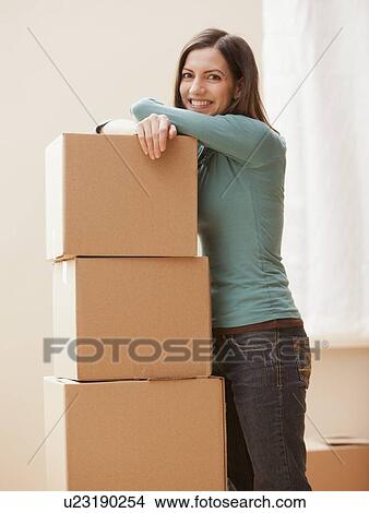 Mid adult woman leaning on cardboard boxes View Large Photo Image Picture - Mid adult woman leaning on cardboard boxes. Fotosearch