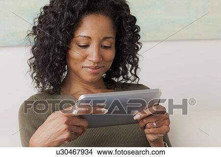 Picture - Mid adult woman using digital tablet. Fotosearch