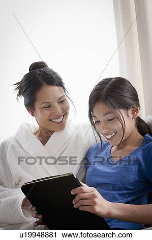 Stock Image - Mother embracing daughter using laptop. Fotosearch