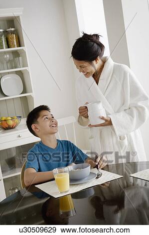 Mother serving breakfast to son View Large Photo Image Stock Photo - Mother serving breakfast to son. Fotosearch