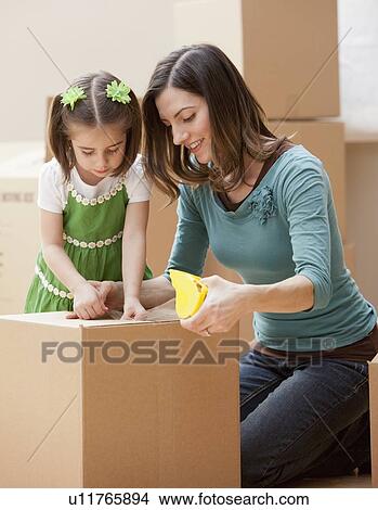 Picture - Mother with daughter (4-5) closing cardboard box. Fotosearch