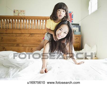 Stock Image - Mother with daughter playing in bedroom (4-5). Fotosearch