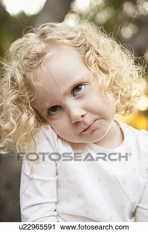 Stock Image - Outdoor portrait of cute blonde girl (4-5) making face. Fotosearch
