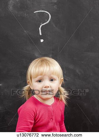 Stock Image - Portrait of baby girl (18-23 months) in front of blackboard. Fotosearch