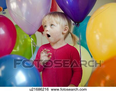 Stock Photograph - Portrait of baby girl (18-23 months) wit colorful balloons. Fotosearch