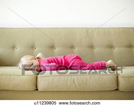 Stock Photography - Portrait of baby girl (18-23 months) resting on sofa. Fotosearch