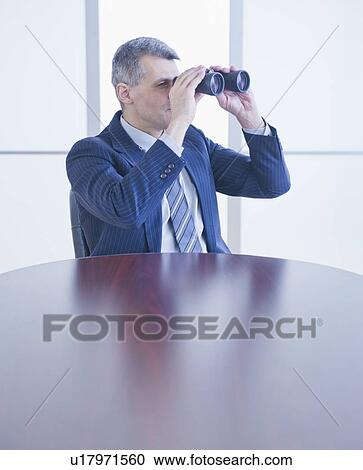 Stock Image - Portrait of businessman holding binoculars. Fotosearch