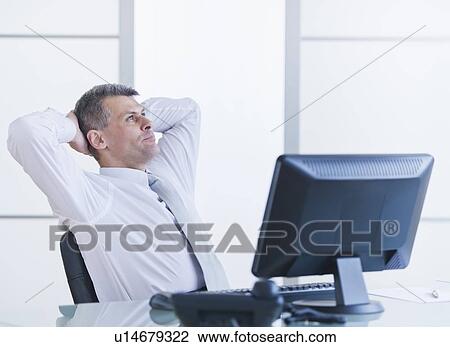 Stock Image - Portrait of businessman relaxing at desk. Fotosearch