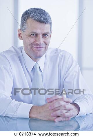 Portrait of businessman sitting at desk View Large Photo Image Picture - Portrait of businessman sitting at desk. Fotosearch