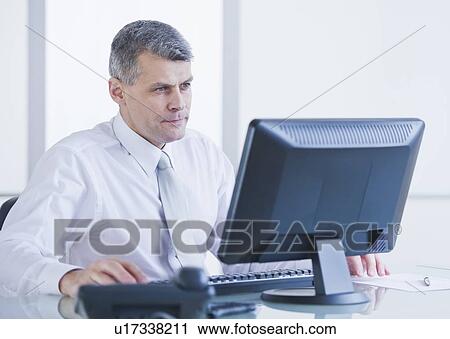 Stock Image - Portrait of businessman working at desk. Fotosearch