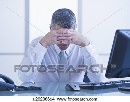 Picture - Portrait of depressed businessman sitting at desk. Fotosearch