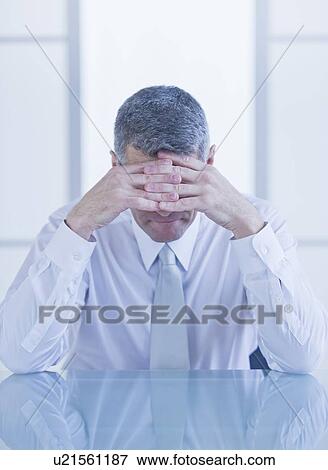 Stock Photo - Portrait of depressed businessman sitting at desk. Fotosearch