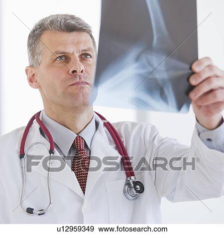 Portrait of doctor looking at x-ray image View Large Photo Image Stock Photo - Portrait of doctor looking at x-ray image. Fotosearch