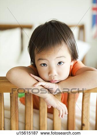 Stock Photo - Portrait of girl leaning on bed frame (2-3). Fotosearch