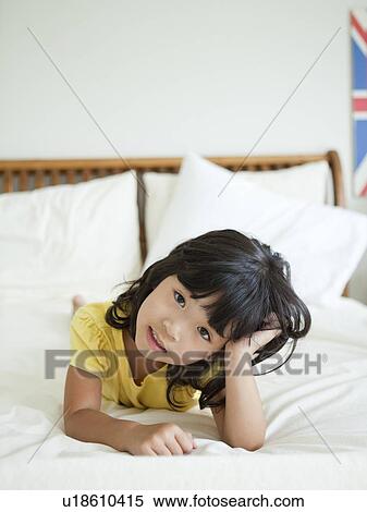 Stock Photography - Portrait of girl lying down in bed (4-5). Fotosearch