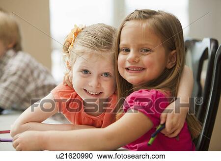 Stock Image - Portrait of girls (4-5) looking at camera in kindergarten. Fotosearch