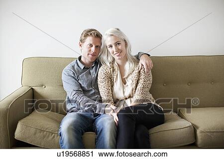 Portrait of happy young couple sitting on sofa View Large Photo Image Stock Image - Portrait of happy young couple sitting on sofa. Fotosearch