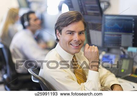 Stock Image - Portrait of male trader at trading desk. Fotosearch