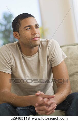 Stock Photo - Portrait of man sitting on sofa. Fotosearch