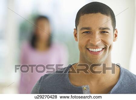 Portrait of man smiling, woman in background View Large Photo Image Stock Photo - Portrait of man smiling, woman in background. Fotosearch