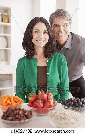 Portrait of mature couple with snacks on table View Large Photo Image Stock Image - Portrait of mature couple with snacks on table. Fotosearch
