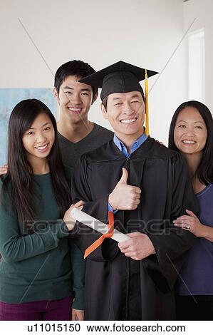 Stock Image - Portrait of mature man in graduation gown with family. Fotosearch
