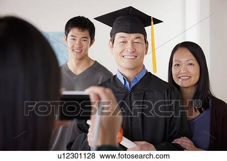 Stock Photo - Portrait of mature man in graduation gown with family. Fotosearch