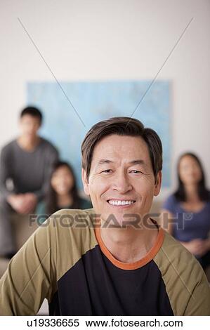 Stock Photography - Portrait of mature man with family in background. Fotosearch