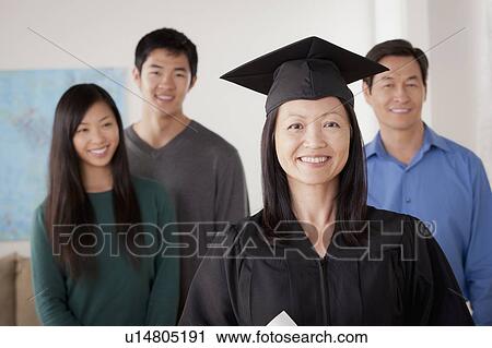 Stock Image - Portrait of mature woman in graduation gown with family. Fotosearch