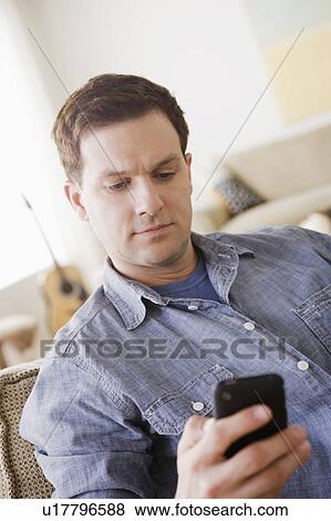 Stock Photo - Portrait of mid adult man using mobile phone. Fotosearch