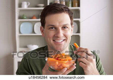 Picture - Portrait of mid adult man with bowl of carrots. Fotosearch