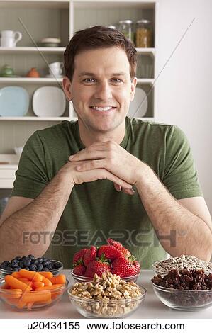 Stock Photography - Portrait of mid adult man with healthy fruits. Fotosearch