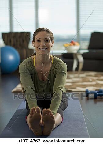 Stock Image - Portrait of mid adult woman exercising at home. Fotosearch