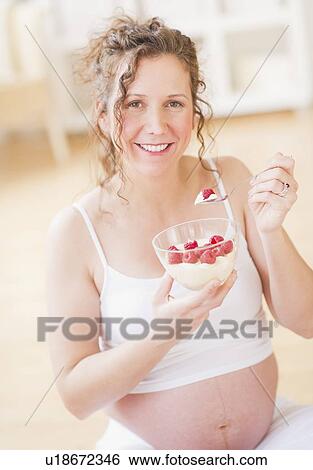 Stock Photograph - Portrait of pregnant woman eating breakfast. Fotosearch