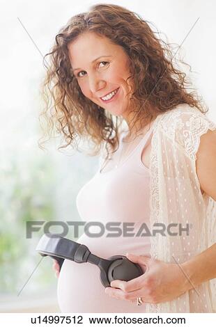 Portrait of pregnant woman holding headphones on her belly View Large Photo Image Stock Image - Portrait of pregnant woman holding headphones on her belly. Fotosearch
