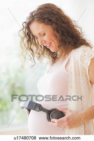 Portrait of pregnant woman holding headphones on her belly View Large Photo Image Stock Photo - Portrait of pregnant woman holding headphones on her belly. Fotosearch
