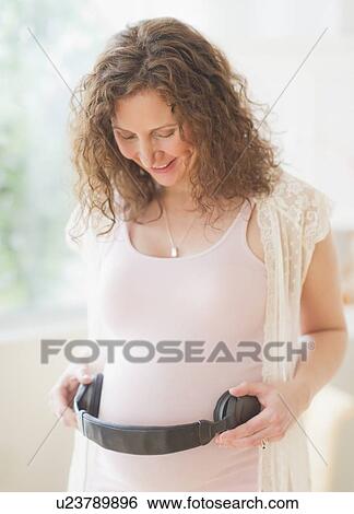 Portrait of pregnant woman holding headphones on her belly View Large Photo Image Stock Photograph - Portrait of pregnant woman holding headphones on her belly. Fotosearch